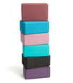Stack of Everyday Yoga Foam Yoga Blocks in various colors, including dark olive, ideal for enhancing stability and support during yoga practice. These lightweight and durable blocks are essential for beginners and experienced yogis alike. Perfect for improving alignment and deepening stretches.