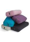 Stack of Everyday Yoga bolsters in various colors, including pink, purple, teal, gray, and black, designed for yoga practice. These yoga props provide support and comfort during poses, enhancing your yoga experience.