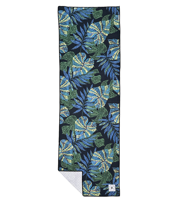 Kaleidoscope Yoga Mat Towel in Neon Jungle design features a vibrant pattern of green and blue tropical leaves. This non-slip towel is perfect for enhancing grip during yoga sessions. Ideal for yogis seeking style and functionality.